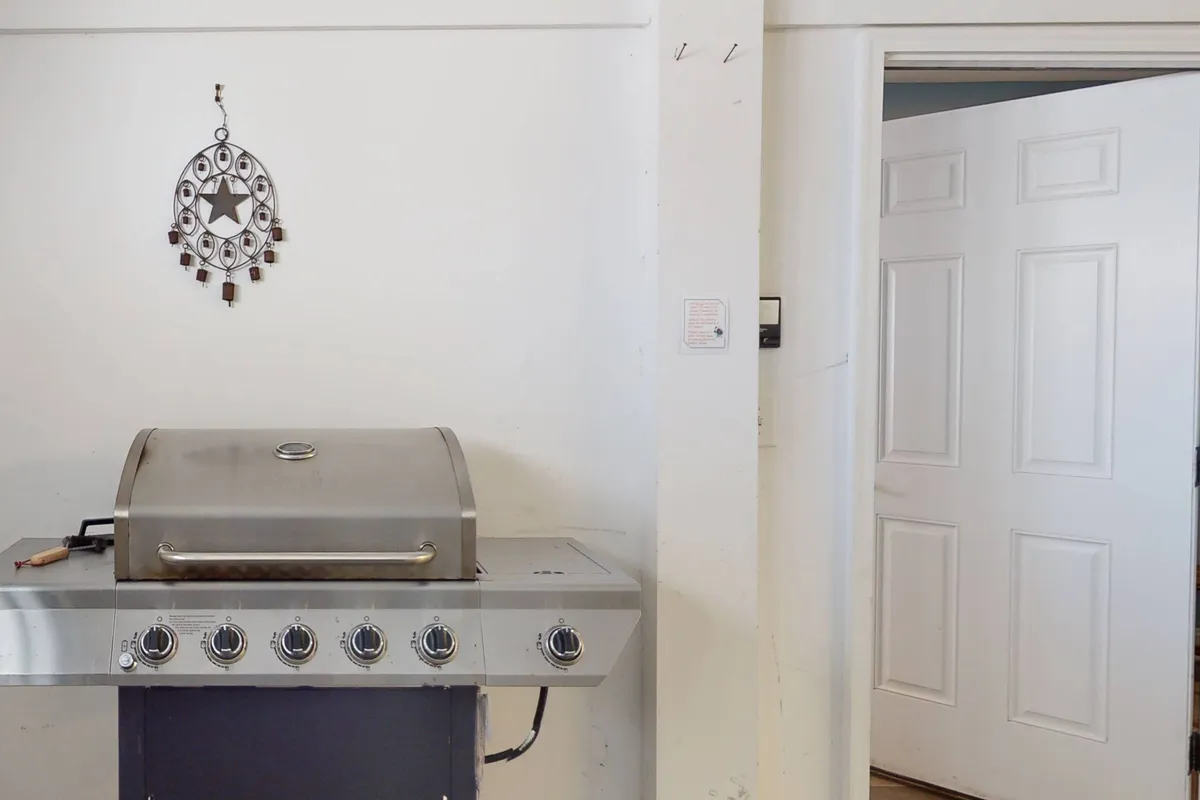 A gas grill is positioned near a doorway, accompanied by simple decor and practical touches. The setup suggests an inviting spot for preparing meals and enjoying casual outdoor dining.