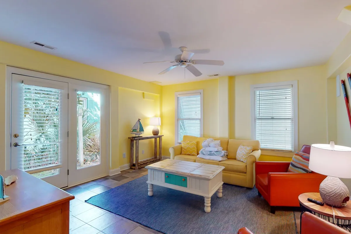 A cozy, welcoming interior living room with yellow walls, a comfortable sofa, colorful armchair, decorative lamp, and coffee table. The space is bright and inviting, ideal for unwinding after exploring with family and pets.
